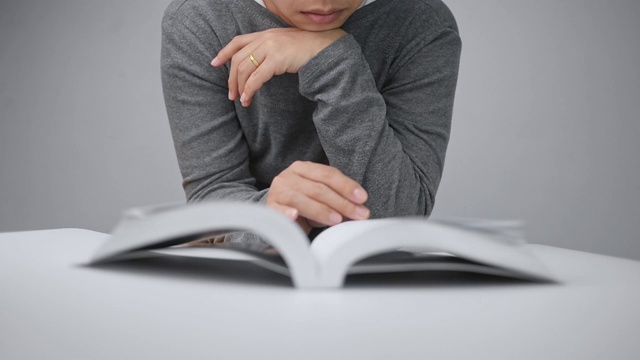 近女人的手翻页的一本书和移动她的手指沿着书页在图书馆阅读。有选择性的重点。视频素材