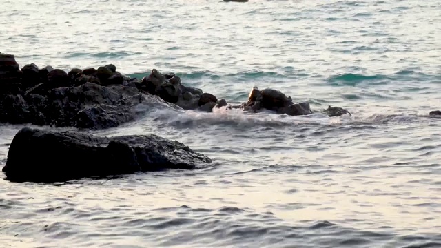 在阳光明媚的日子里，在Koh larn岛的天然石滩和溅起浪花的海水。视频素材