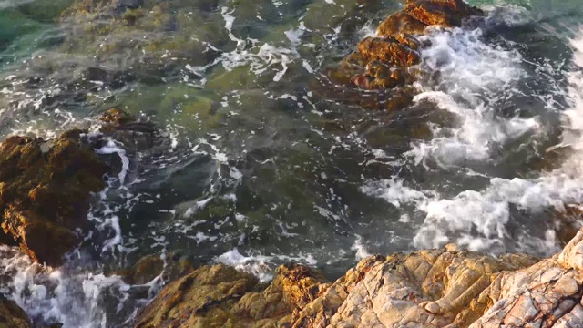 在阳光明媚的日子里，在Koh larn岛的天然石滩和溅起浪花的海水视频素材