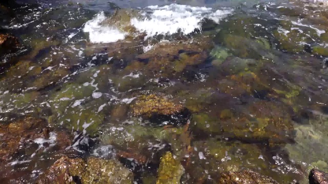 在阳光明媚的日子里，在Koh larn岛的天然石滩和溅起浪花的海水。视频素材