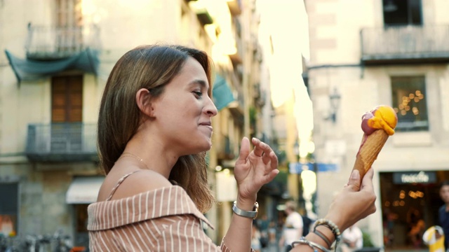 可爱的女孩吃冰淇淋的慢镜头。笑着对着相机摆姿势的女人视频素材