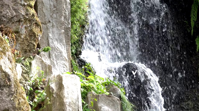 近距离观察瀑布。水流过岩石峭壁流入一个深水池。视频素材