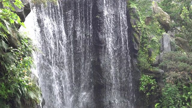 近距离观察瀑布。水流过岩石峭壁流入一个深水池。视频素材