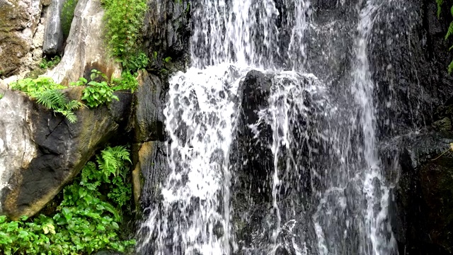 近距离观察瀑布。水流过岩石峭壁流入一个深水池。视频素材