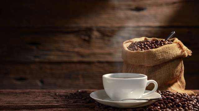 在古老的木制背景上，一杯带有烟和咖啡豆的咖啡视频素材