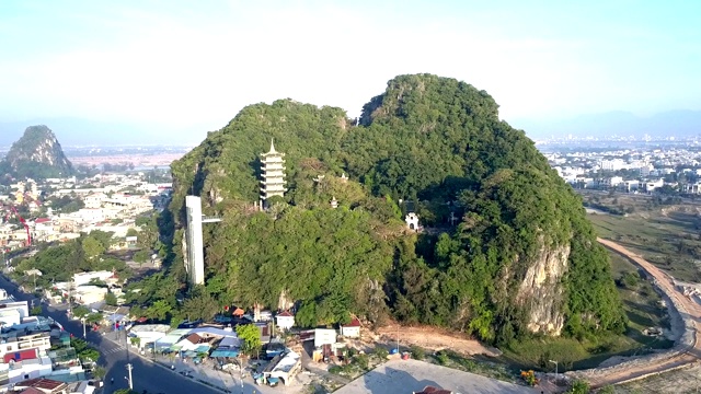 鸟瞰图城市间有寺庙的单一绿色山丘视频素材