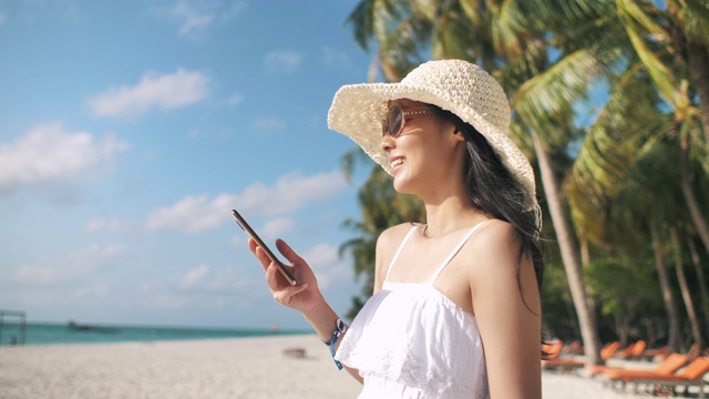 亚洲女人在海滩上使用智能手机视频素材