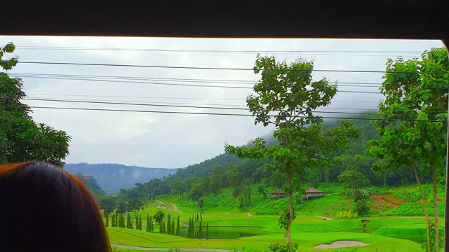 火车正在运行，早晨可以看到山景、天空、绿色的田野和雾。视频素材