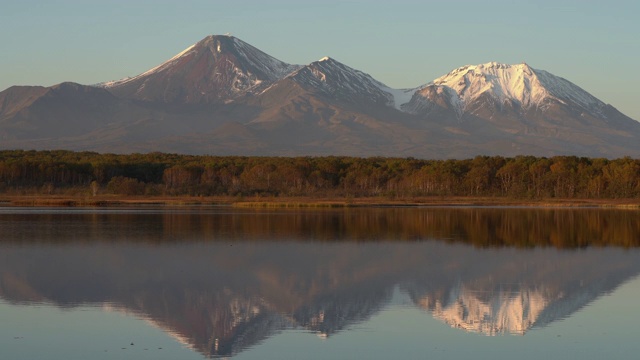 秋季全景火山景观在黄金时间:火山，黄橙色森林和山上湖泊的倒影视频素材