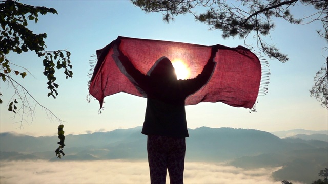 女人在山上对着日出玩围巾的慢镜头视频素材