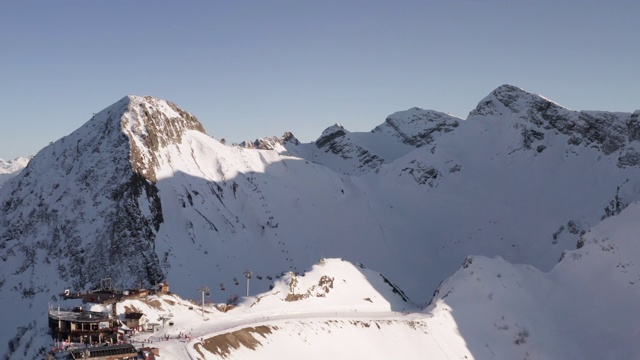 鸟瞰图雪山山顶上的滑雪胜地。在山上的雪坡上运送滑雪者和滑雪板的无人机滑雪电梯。从无人机俯瞰冬季滑雪胜地视频素材