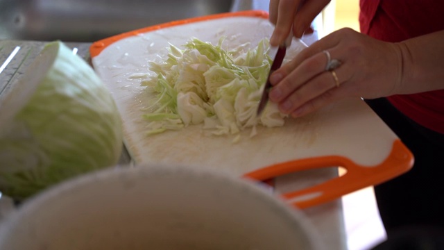 在家里的砧板上切新鲜的生卷心菜。在厨房准备素食。新鲜卷心菜沙拉，健康营养和饮食理念视频素材