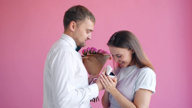 穿着优雅的男子正在给微笑着的幸福年轻女子送花和戒指视频素材