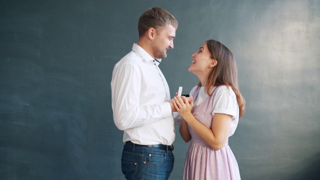 英俊的男人向漂亮的女孩求婚，把订婚戒指放在首饰盒里视频素材