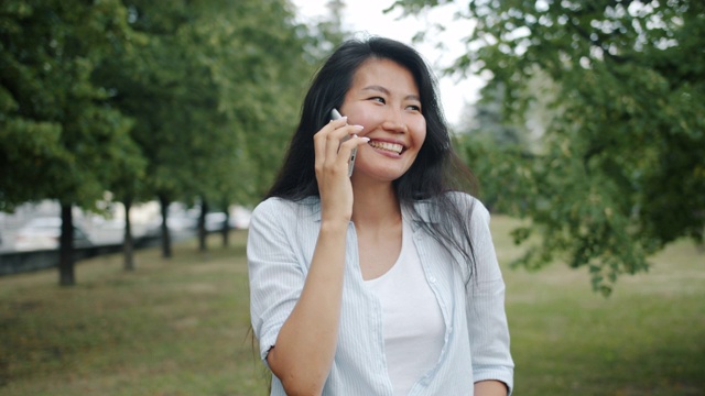 快乐的亚洲女学生聊天在夏季的绿色公园手机视频素材