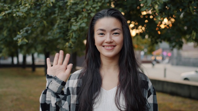 慢动作的年轻亚洲女子挥手微笑看着镜头在公园视频素材