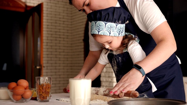 母亲和女儿一起在厨房里擀饼干面团。视频素材