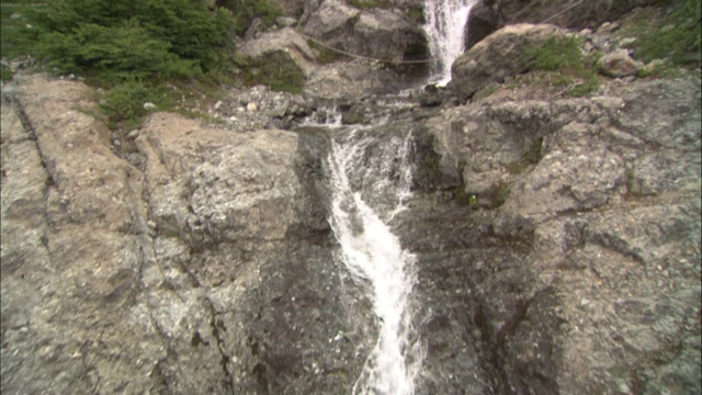 登山者攀登靠近瀑布和湖泊的岩石面。视频素材