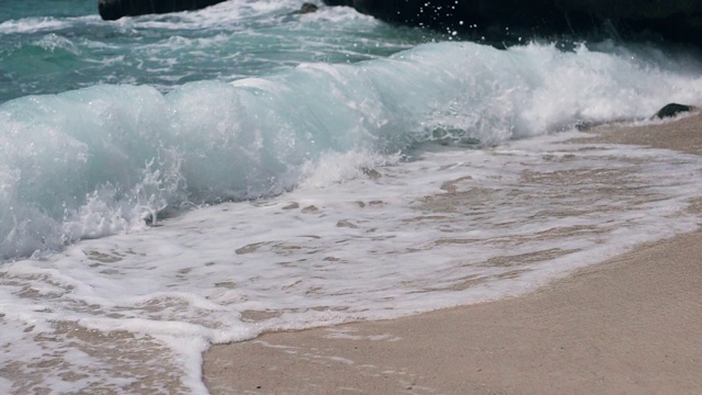 白色的沙滩上，汹涌的海浪拍打着海浪的泡沫。视频素材