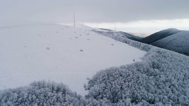 冬天的鸟瞰图。无人机飞越白雪皑皑的山脉，在冬季的大雾天气中景观。视频素材