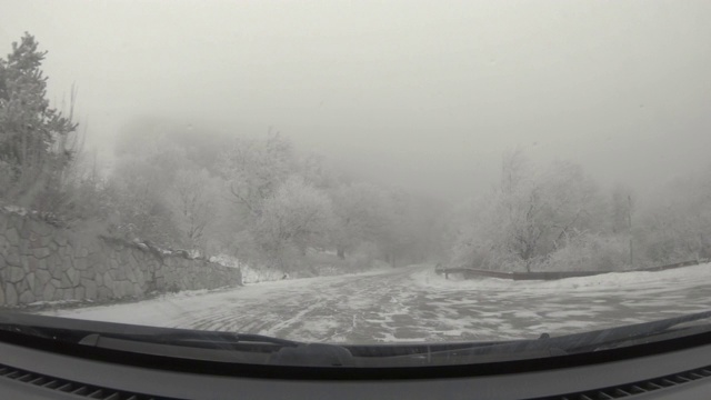 汽车POV在积雪覆盖的路上行驶，先下起了雪。视频素材