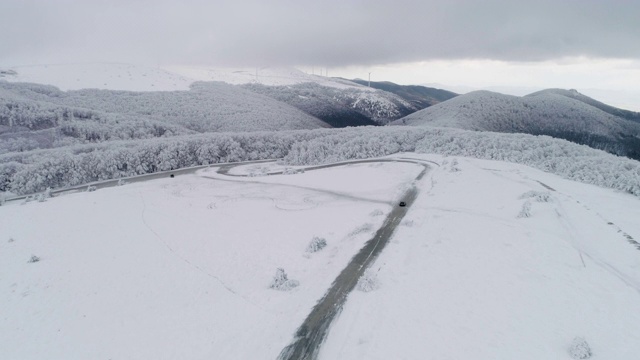 冬季空中公路旅行。无人机飞越白雪皑皑的山脉，在冬季的大雾天气中景观。视频素材