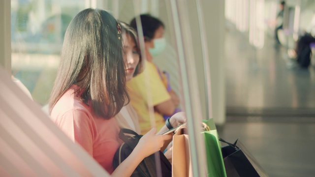 两个年轻的亚洲女人在火车上一边聊天一边用手机，慢镜头视频素材