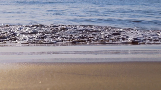 轻柔的海浪从大海来到潮湿的沙滩。视频素材