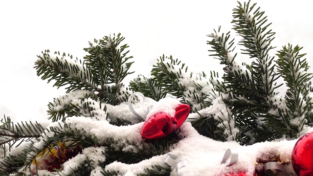 圣诞树的树枝上装饰着雪下的玩具。视频素材