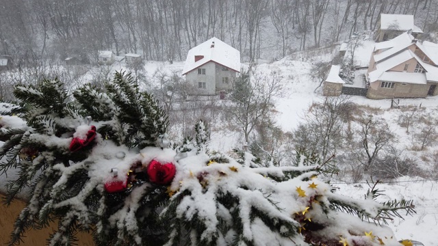 圣诞树的树枝上装饰着雪下的玩具。以森林和房屋为背景拍摄。视频素材