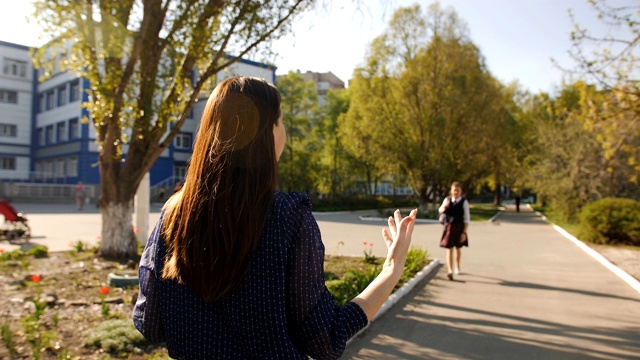 放学后，妈妈在学校附近遇到一个十几岁的女儿。13岁的女孩穿着校服走出教学楼迎接母亲。视频素材