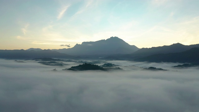 4K航拍镜头令人惊叹的美丽的自然景观，在日出与最大的基纳巴卢山与雾在沙巴州，婆罗洲农场视频素材