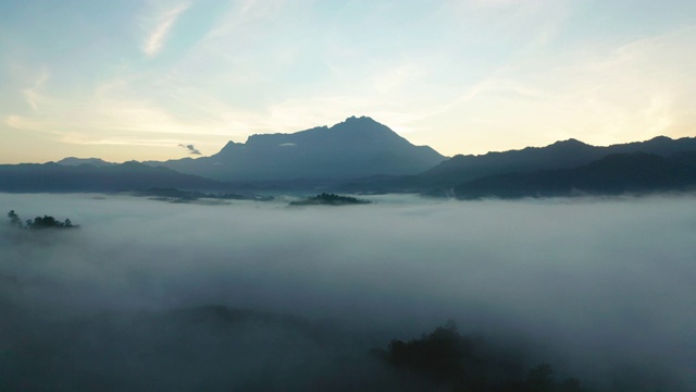 4K航拍镜头令人惊叹的美丽的自然景观，在日出与最大的基纳巴卢山与雾在沙巴州，婆罗洲农场视频素材