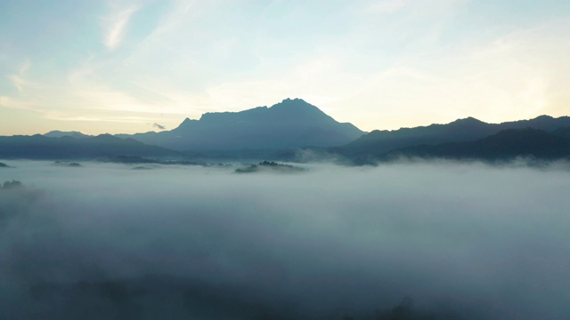 4K航拍镜头令人惊叹的美丽的自然景观，在日出与最大的基纳巴卢山与雾在沙巴州，婆罗洲农场视频素材