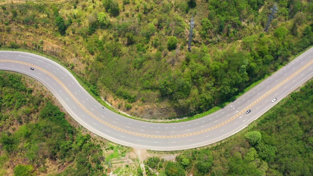 鸟瞰图，弯曲的道路通过森林与汽车移动。倾斜了。视频素材