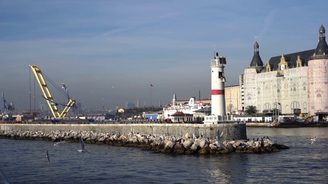 在Kadikoy有灯塔和码头的Haydarpasa火车站大楼和海鸥在慢镜头中飞翔视频素材