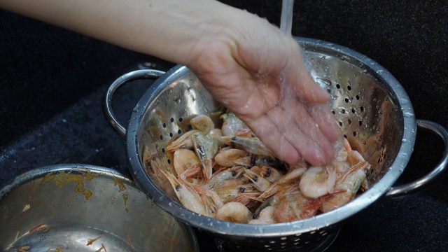 厨师烹饪海鲜。在厨房里准备虾的女人。厨师正在水槽里洗虾。家乡菜。洗虾的过程视频素材