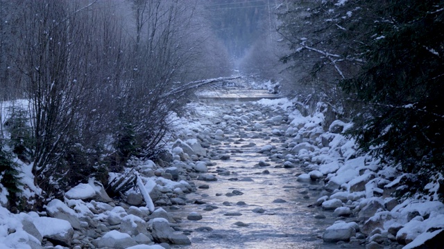 一条雾蒙蒙的山川流过一片白雪皑皑的景色。视频素材