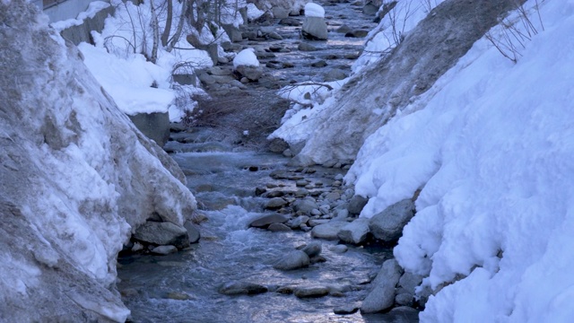 一条雾蒙蒙的山川流过一片白雪皑皑的景色。视频素材