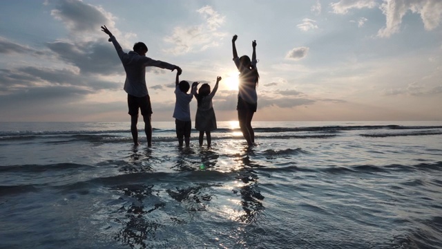 父亲，母亲，儿子和女儿一起在海滩上玩水和海。背景夕阳在海上。放松假期和旅游的概念。慢动作视频素材