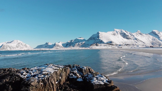 沙滩下的雪景映衬着群山的背景，下面是广阔的蓝天。视频素材