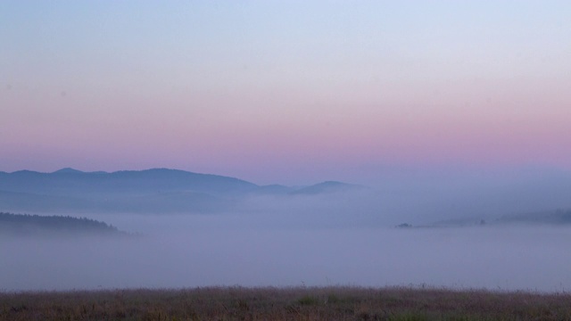 4K自然山景观与雾黄昏与田野在前景。视频素材