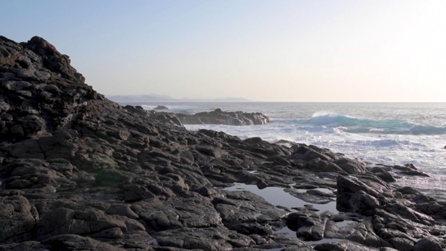 在兰萨罗特岛，岩石嶙峋的海岸线与汹涌的大海和清澈的金色天空相映成辉视频素材