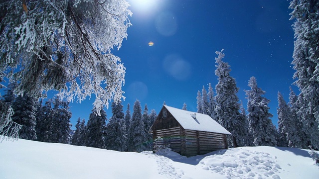 白雪覆盖的小屋和森林映衬着冬日的蓝天。间隔拍摄视频视频素材