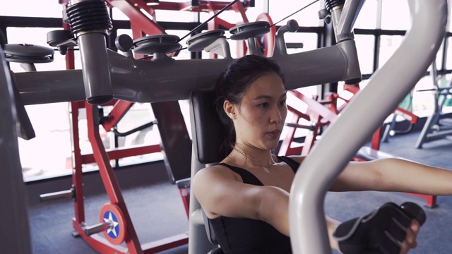 女性用重杠铃卧推机在健身馆锻炼健康的生活方式，锻炼肌肉，体育运动女性训练耐力强集中胸部锻炼。4K超高清影片视频素材