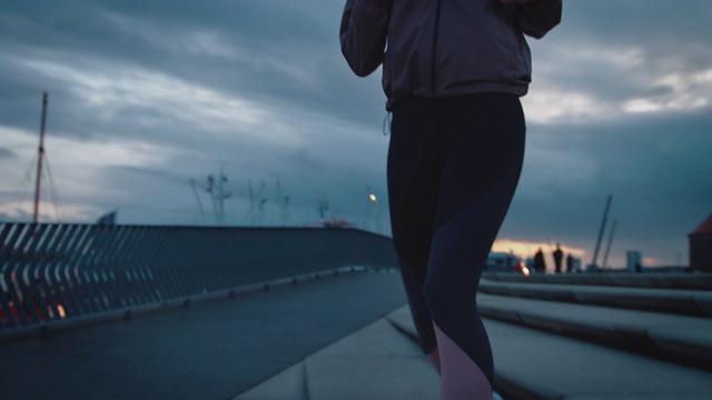 黄昏时分，年轻的女运动员在散步路上慢跑视频素材