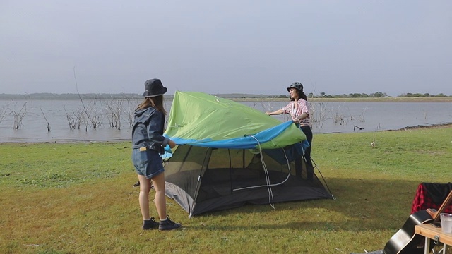 一群亚洲朋友在夏天一起喝酒和弹吉他，在日落时分在湖边露营视频素材