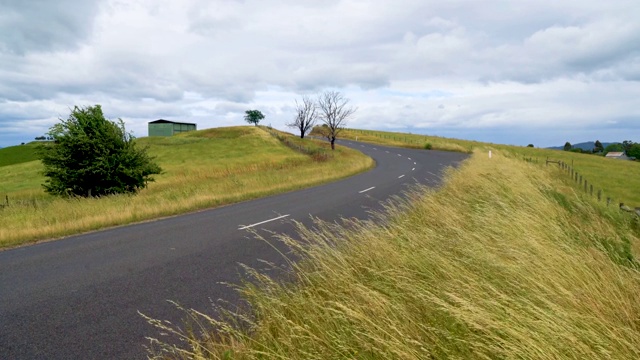 在刮风的日子里，道路和草地的景色视频下载