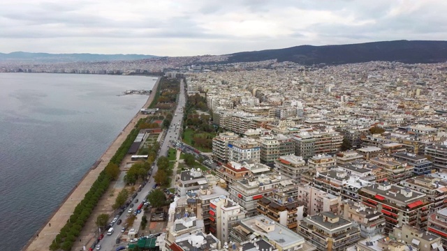 鸟瞰图城市海岸线在塞萨洛尼基市，建筑和公园，多云的天空，冬季，侧面移动的无人机视频下载