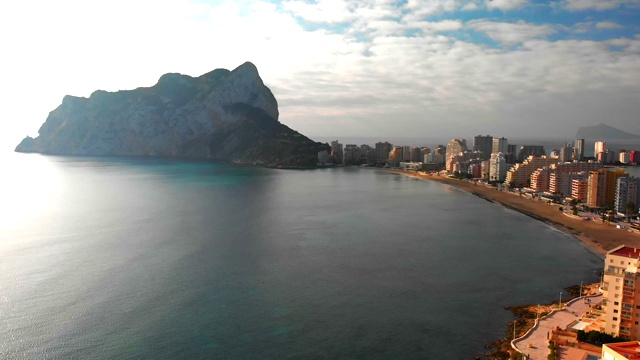 西班牙阿利坎特卡尔佩市日出时的鸟瞰图。La Fossa海滩在前景和de Ifach Penon岩石在背景。视频素材